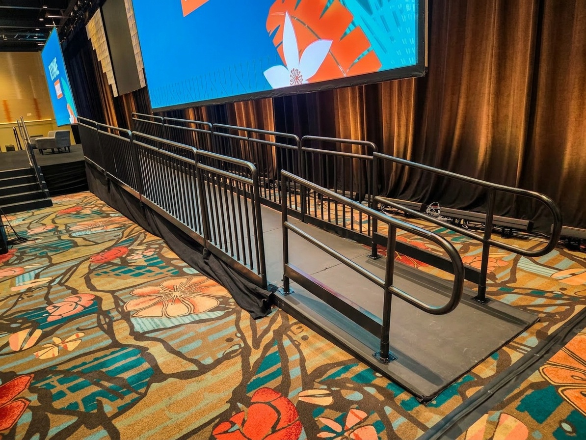 Close-up of a professional stage ramp with guard rails and non-slip surface at an indoor event venue in Orlando
