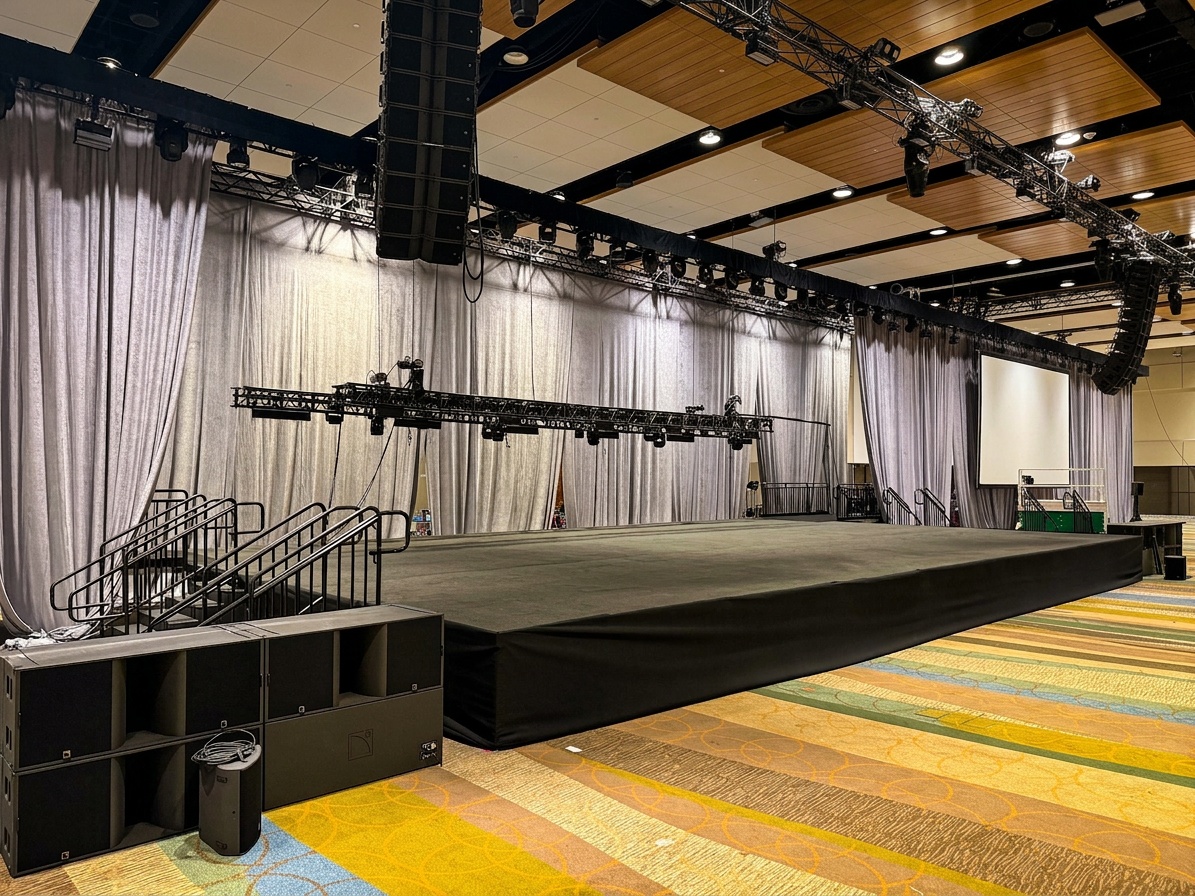 Stages Plus crew unloading stage components from a truck at an indoor Central Florida venue, daylight exterior shot