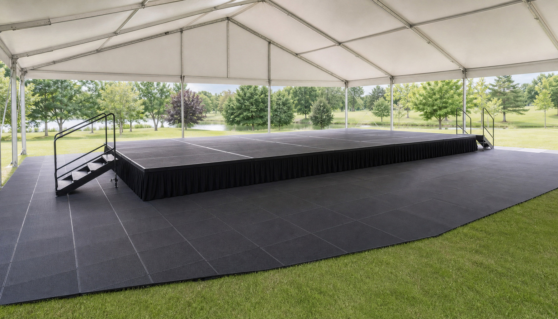 Stages Plus stage setup at an outdoor venue with tent flooring, showing the full footprint from a wide-angle perspective