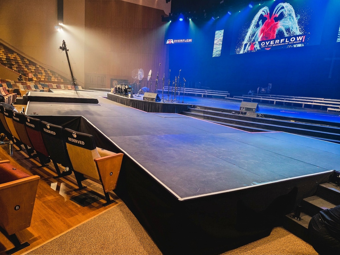 crew running cable and rigging truss lighting above a stage before an event