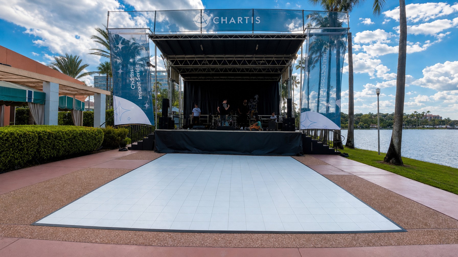 two portable concert stages set up at opposite ends of an event space with bands preparing gear