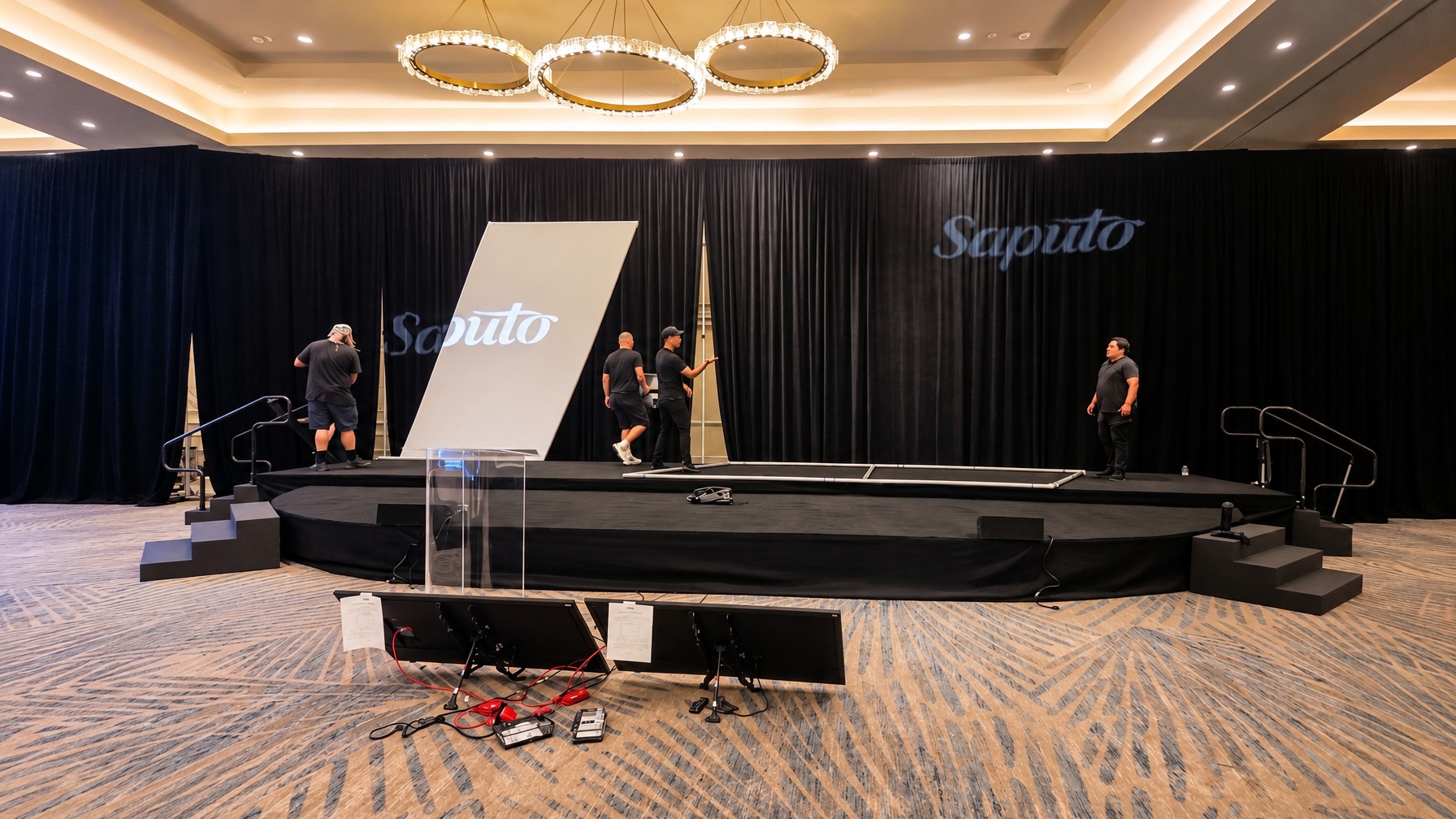 AV technician testing lighting and sound circuits on a stage deck before decor install