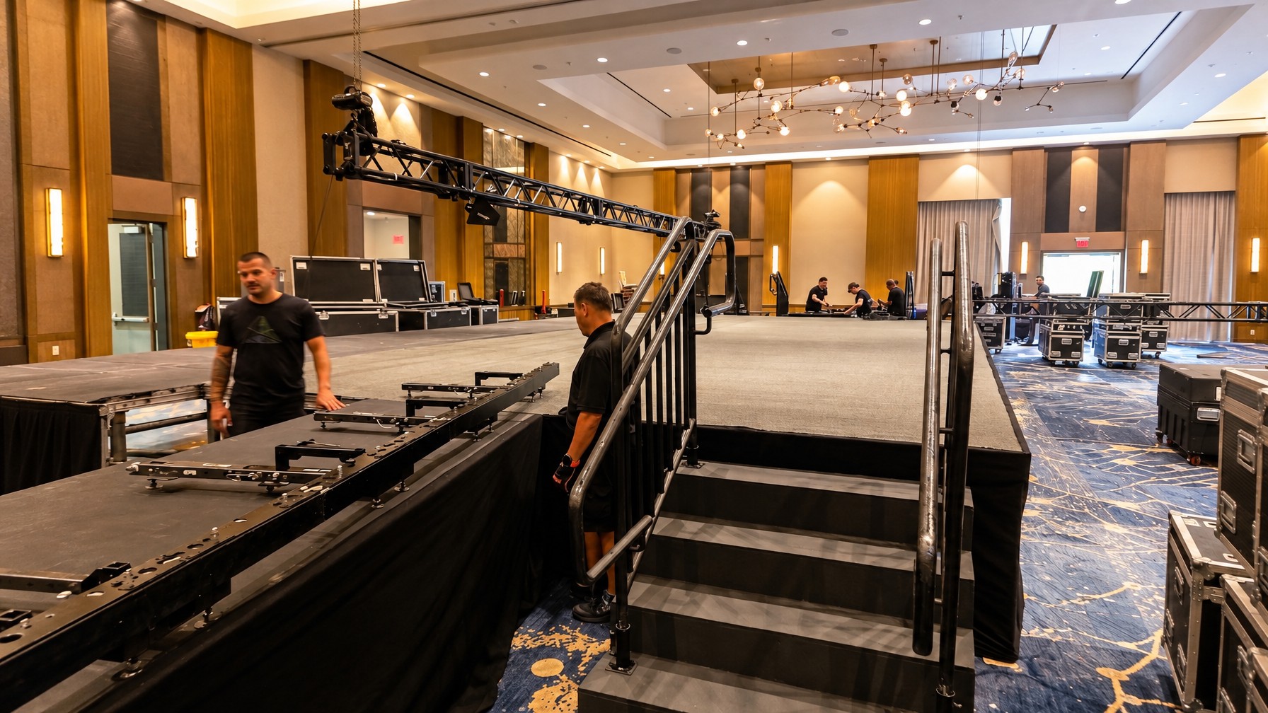 stage crew assembling a deck and guard rails before AV cables are run, Central Florida event venue