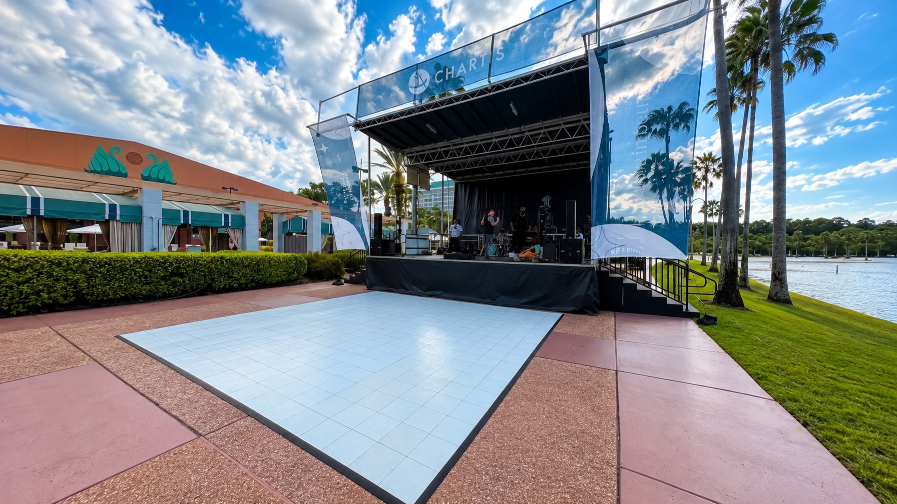 Stages Plus crew assembling a modular stage deck section by section at a Central Florida outdoor event